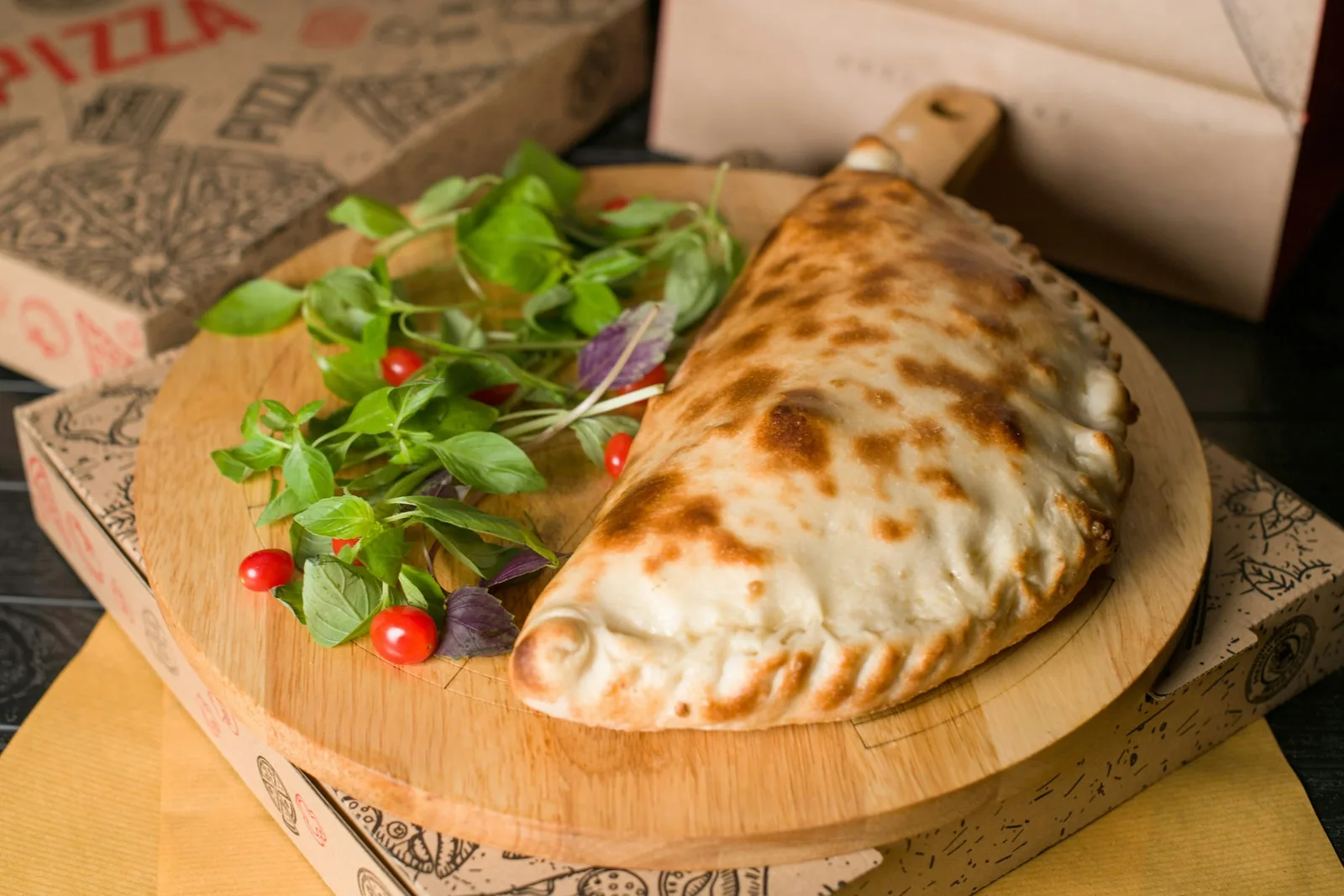 A whole baked calzone served on a wooden board