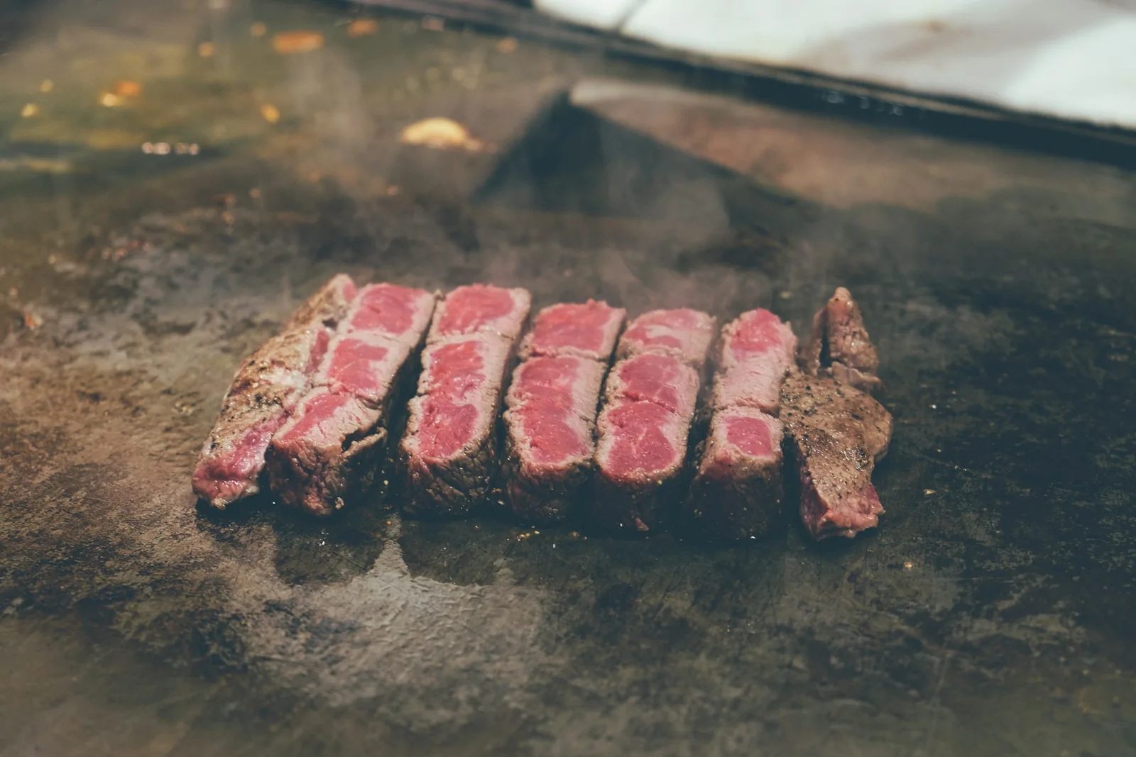 Sliced beef cooking on a griddle