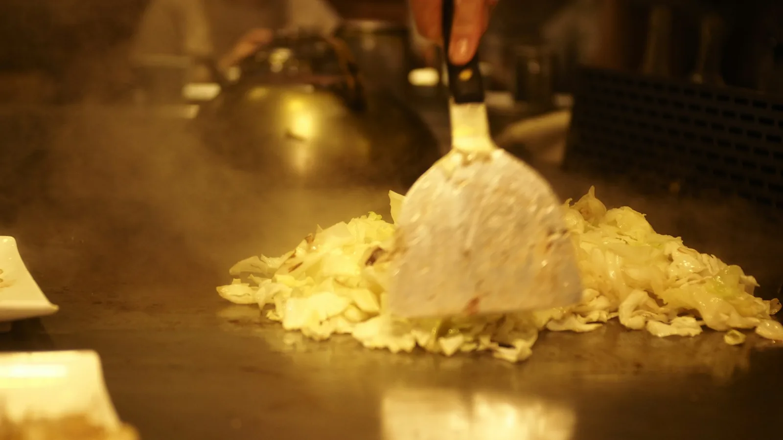 A spatula chopping meat on a griddle