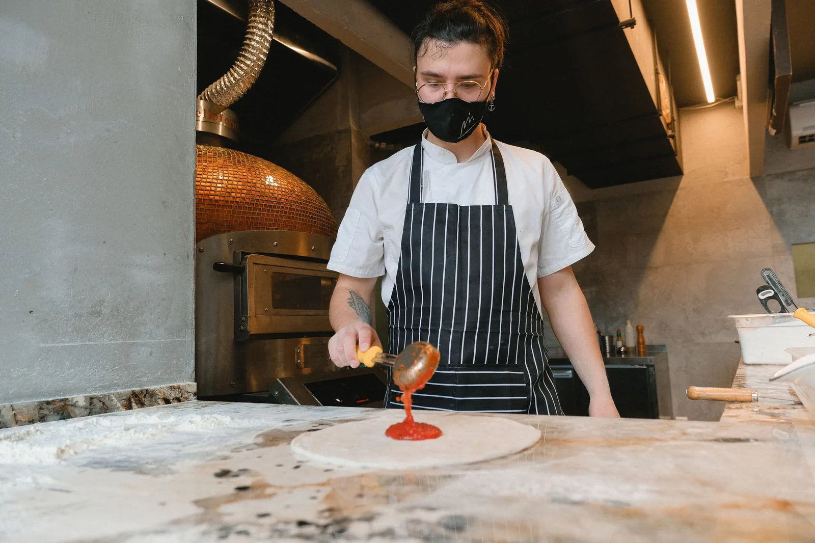Sauce being ladled onto a pizza base