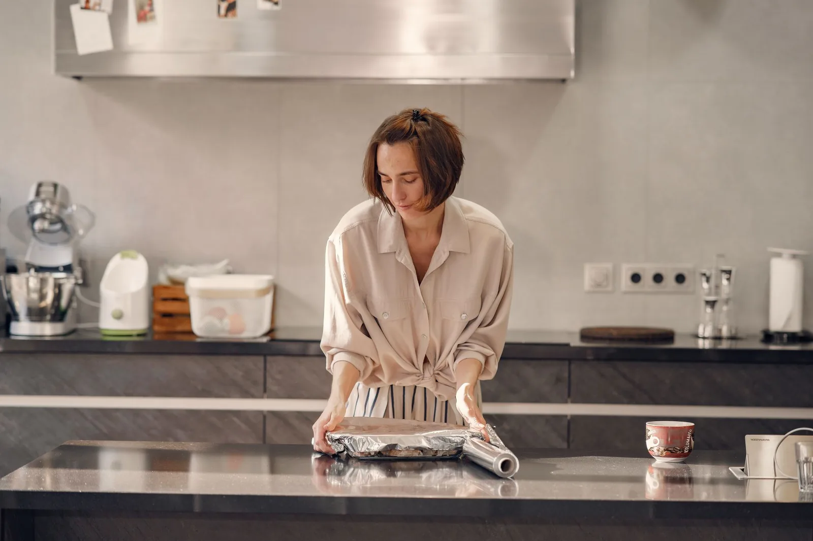 Tearing a sheet of foil at a kitchen counter