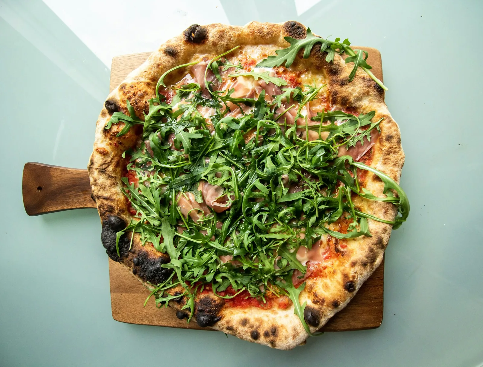 A pizza finished with fresh leaves