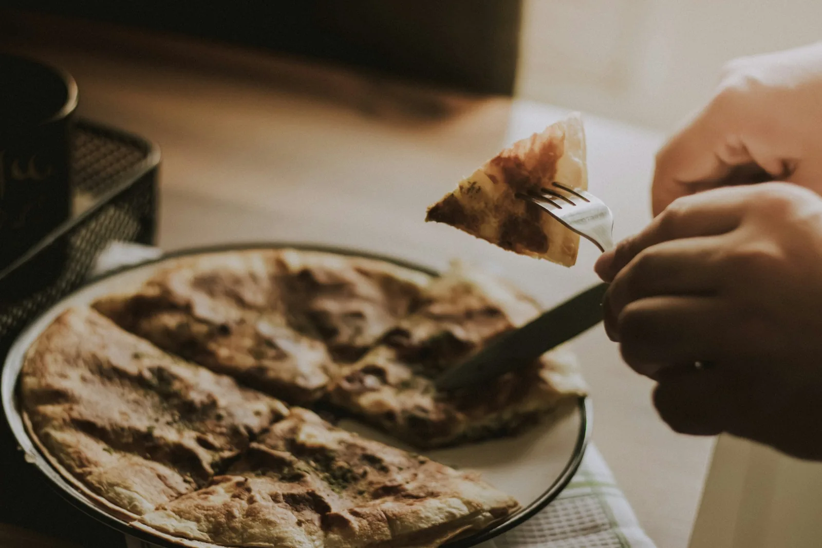 A pizza slice being lifted from a plate
