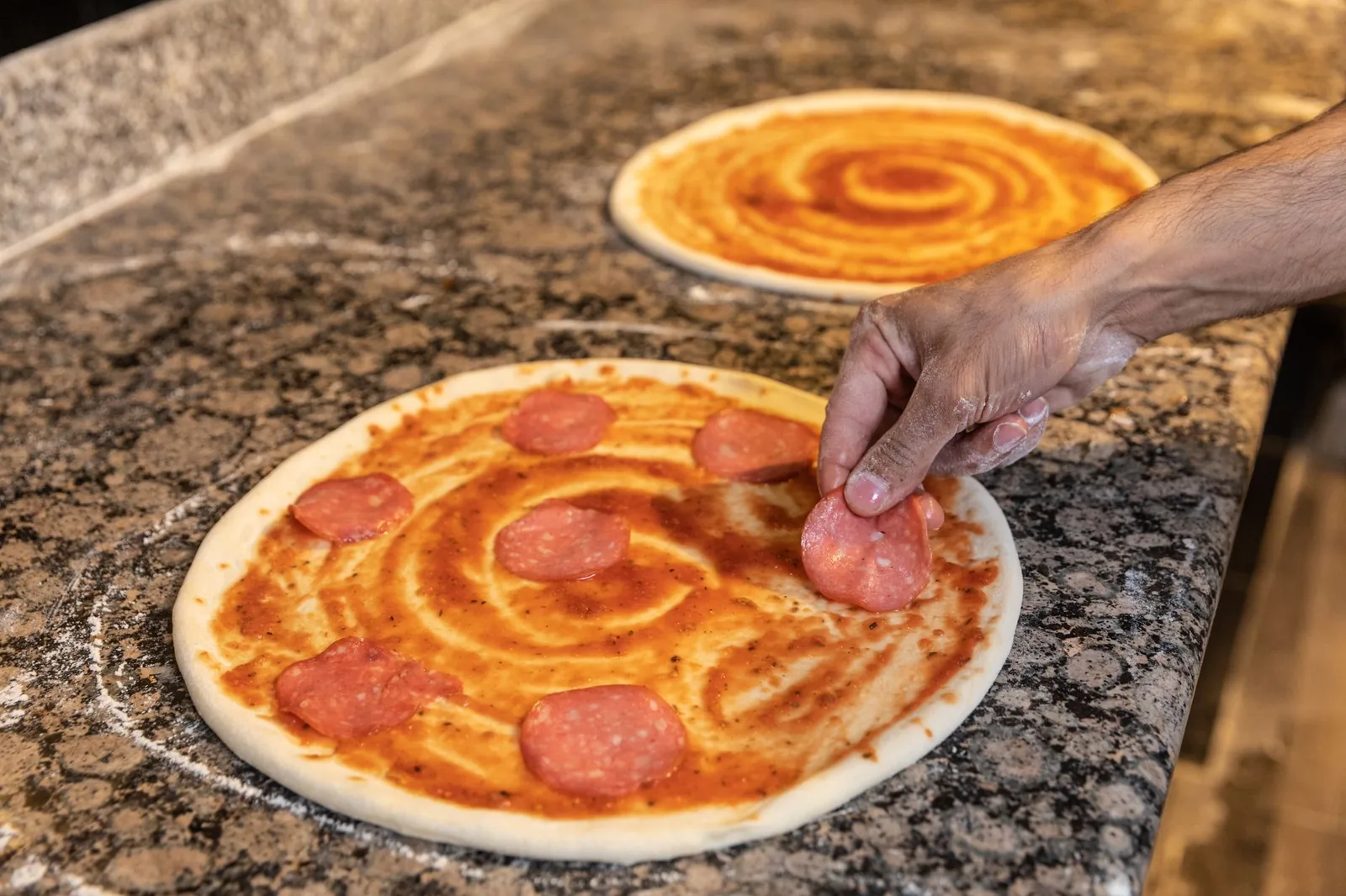 A pizza base being topped