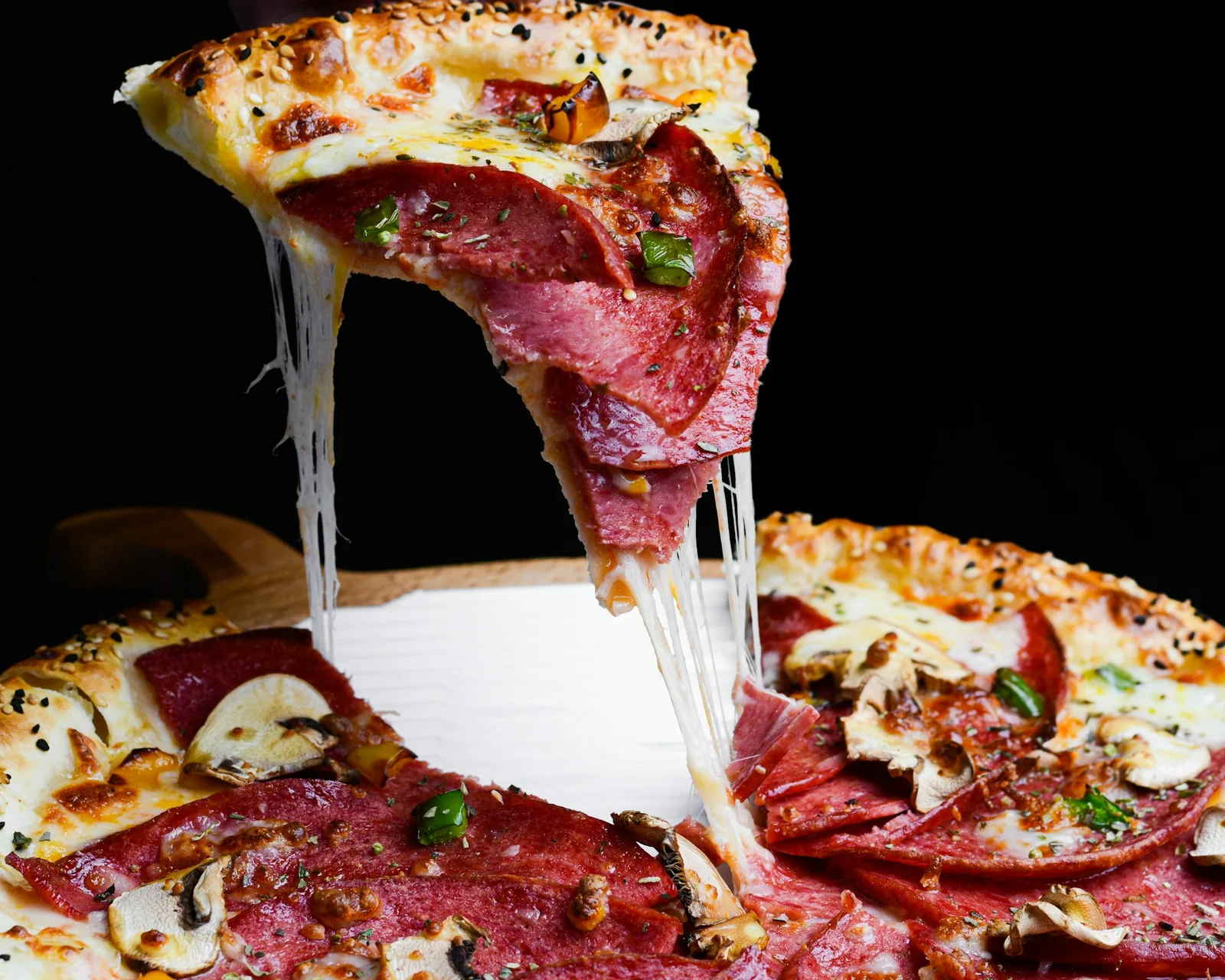 Pepperoni pizza slices being lifted