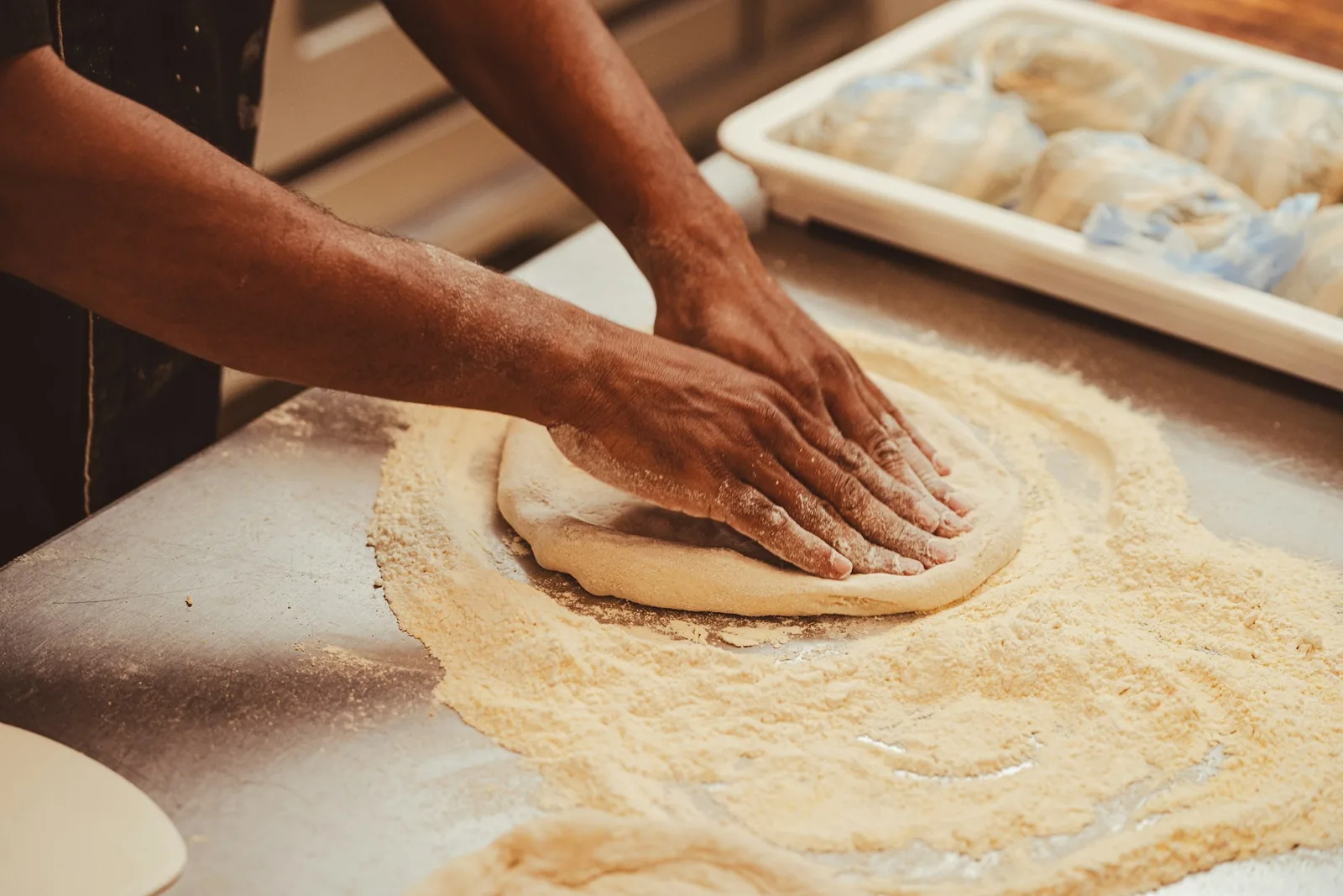 Hands working a round of pizza dough