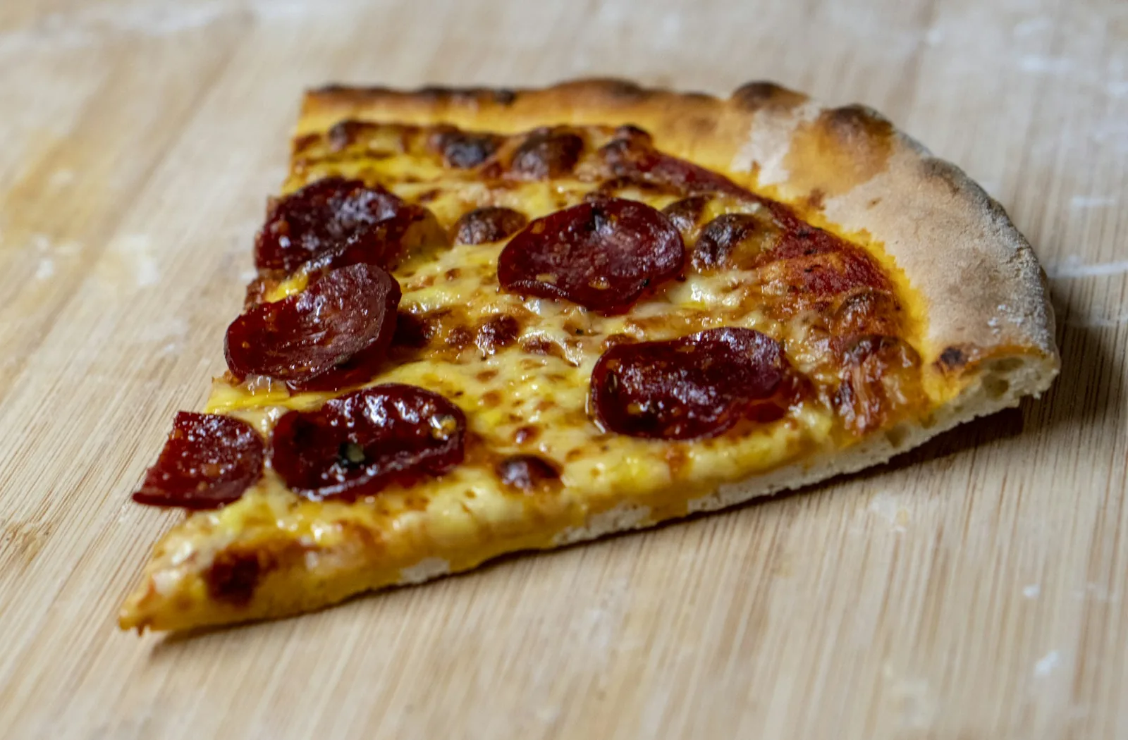A pepperoni slice being lifted