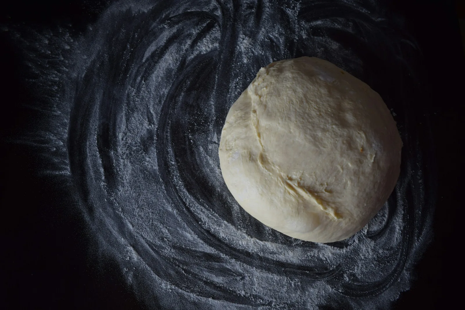 A ball of pizza dough proofing in a bowl