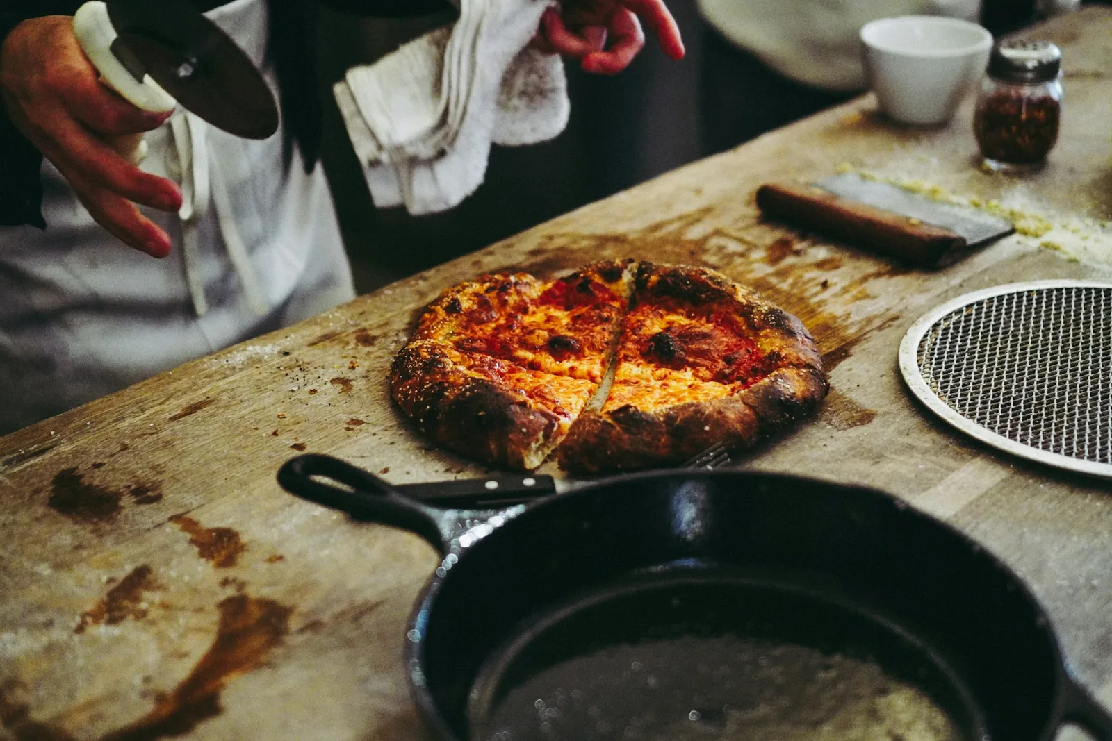 A whole pizza on a board beside a cast-iron skillet