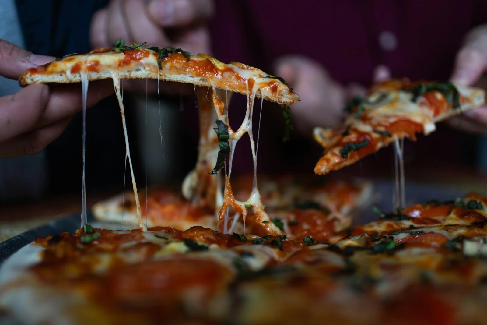 A slice of pizza being lifted, cheese stretching