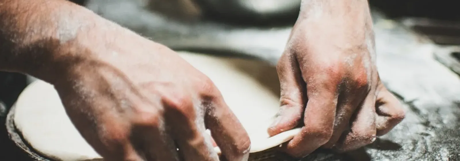 Pizza dough being stretched by hand