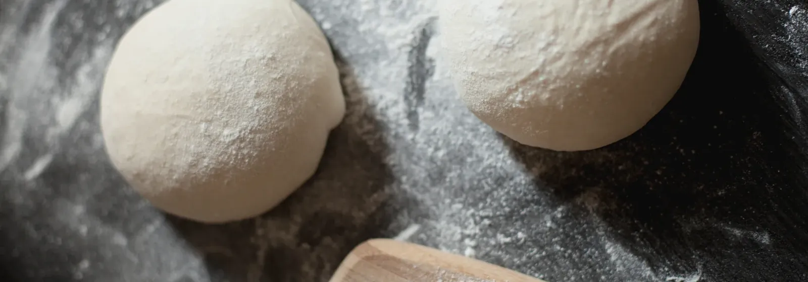 Balls of fresh pizza dough resting on a floured surface