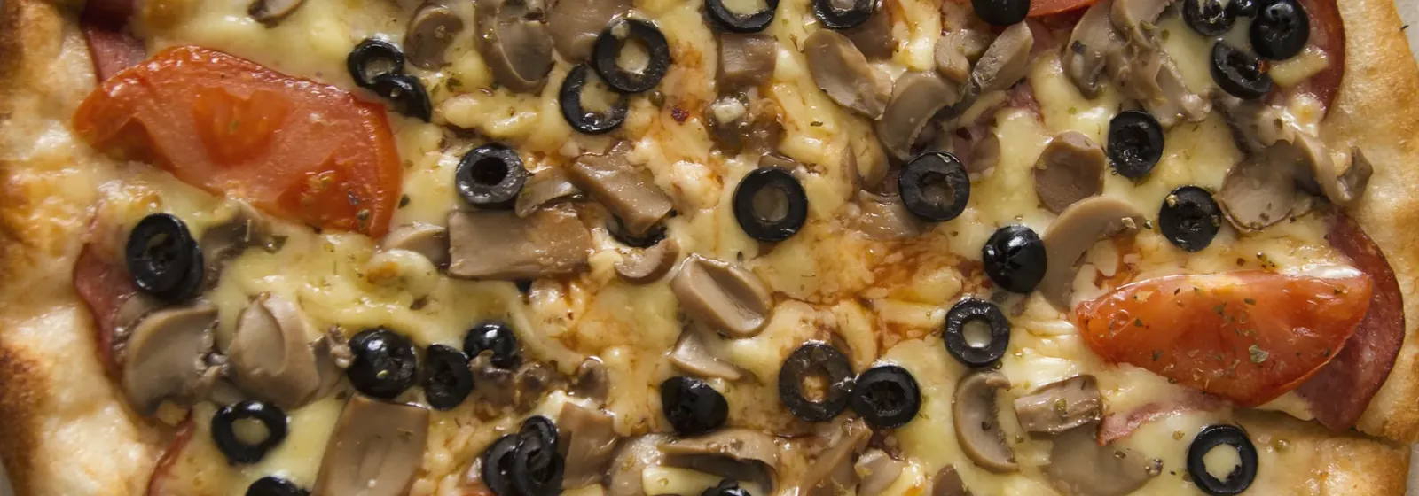 Whole pizza topped with olives, mushrooms and sliced tomato