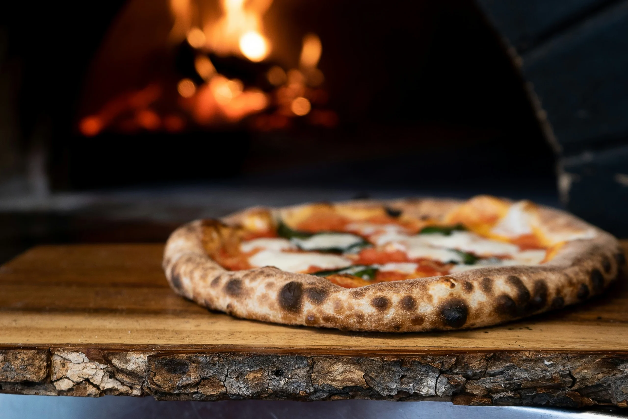 A pizza baking in a wood-fired oven