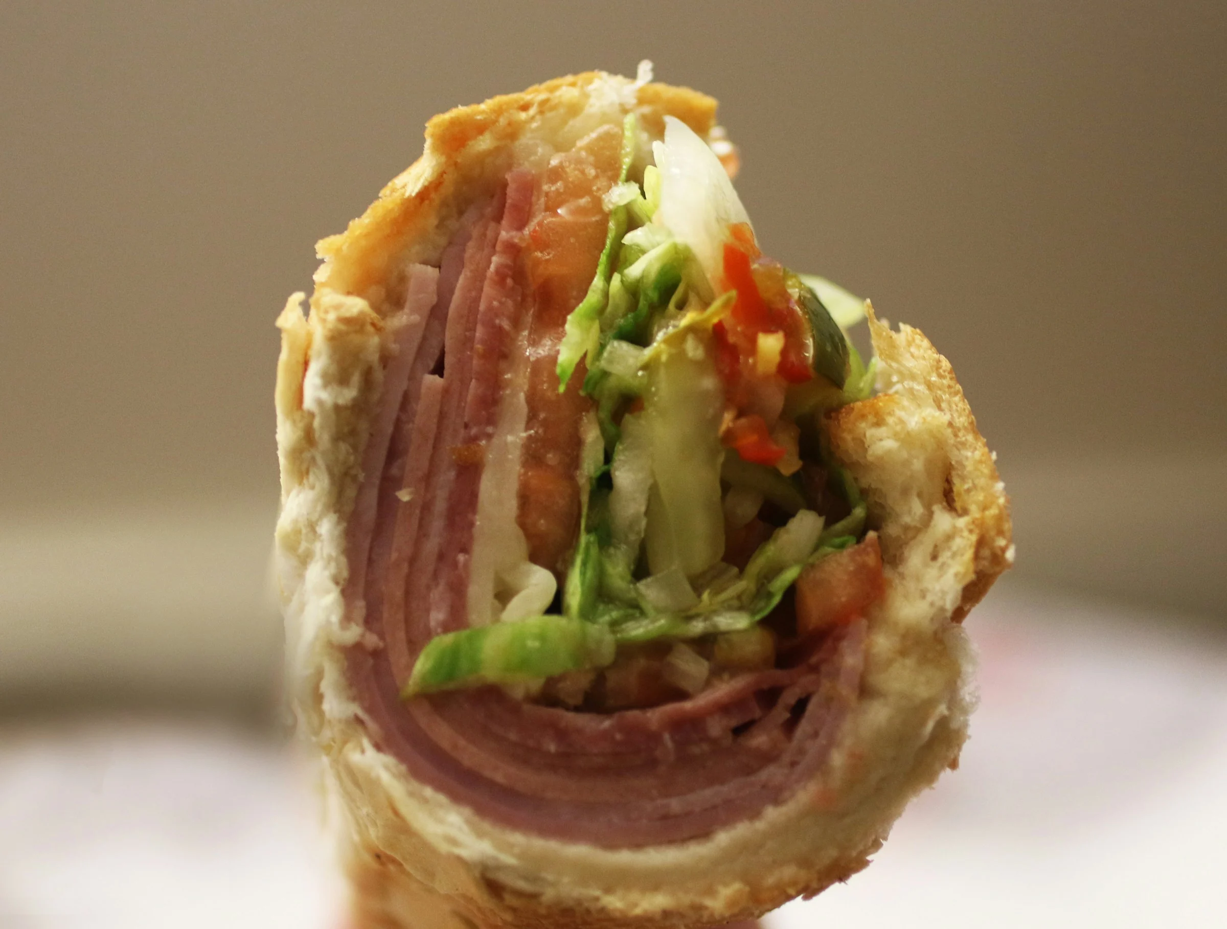 An Italian sub filled with cured meats, cheese and salad