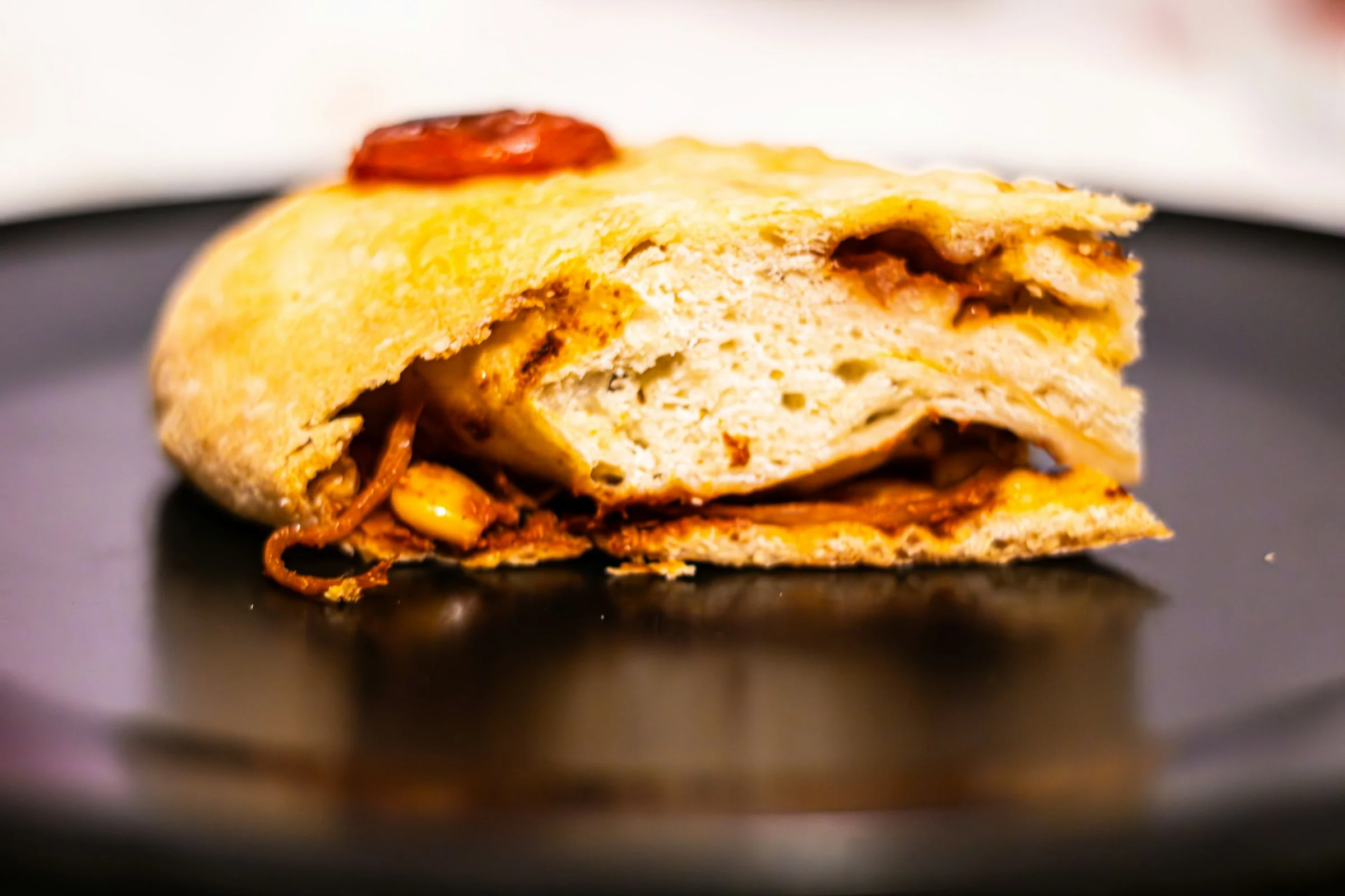 A baked calzone cut open on a dark plate
