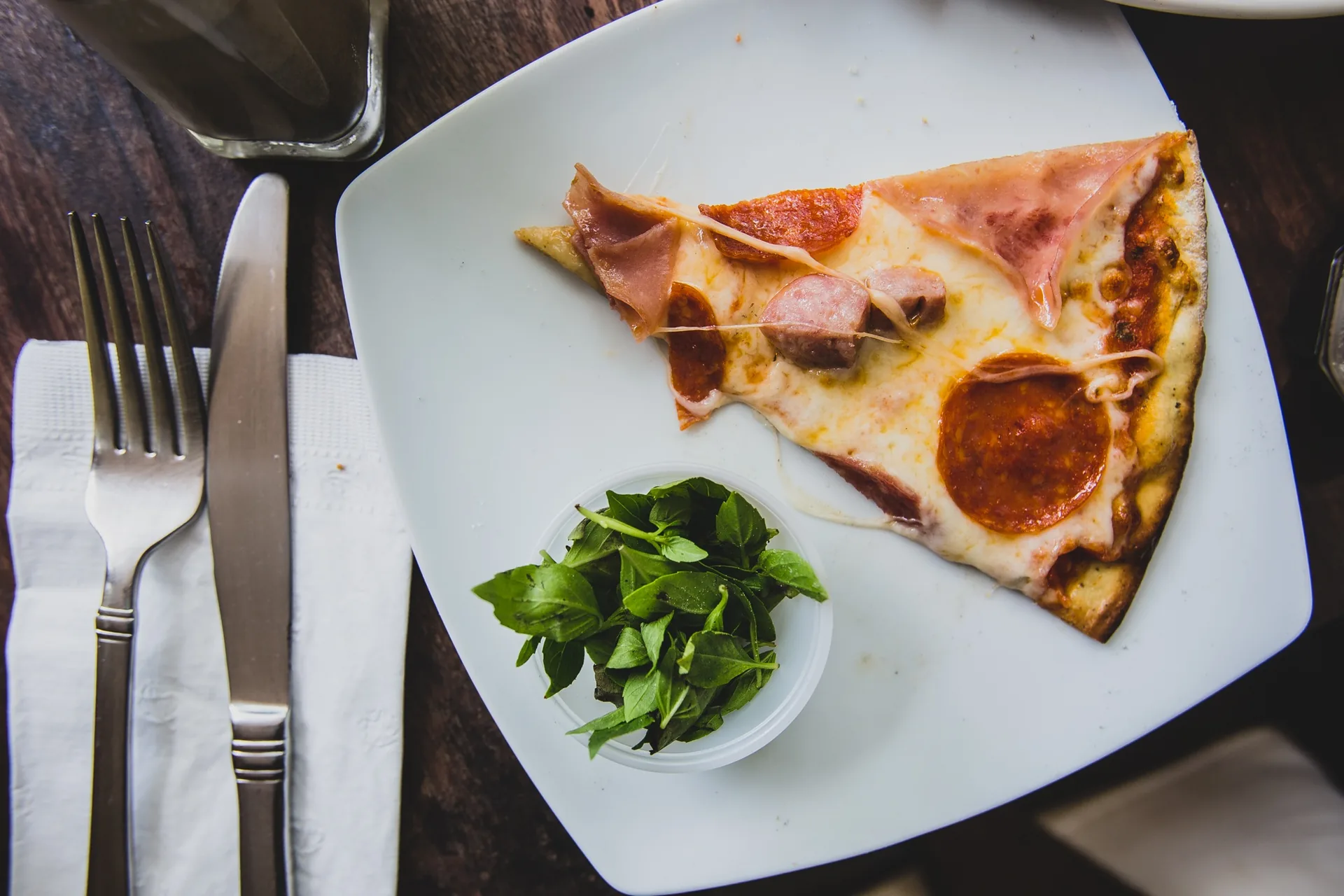 Single slice of pepperoni and sausage pizza on a white plate