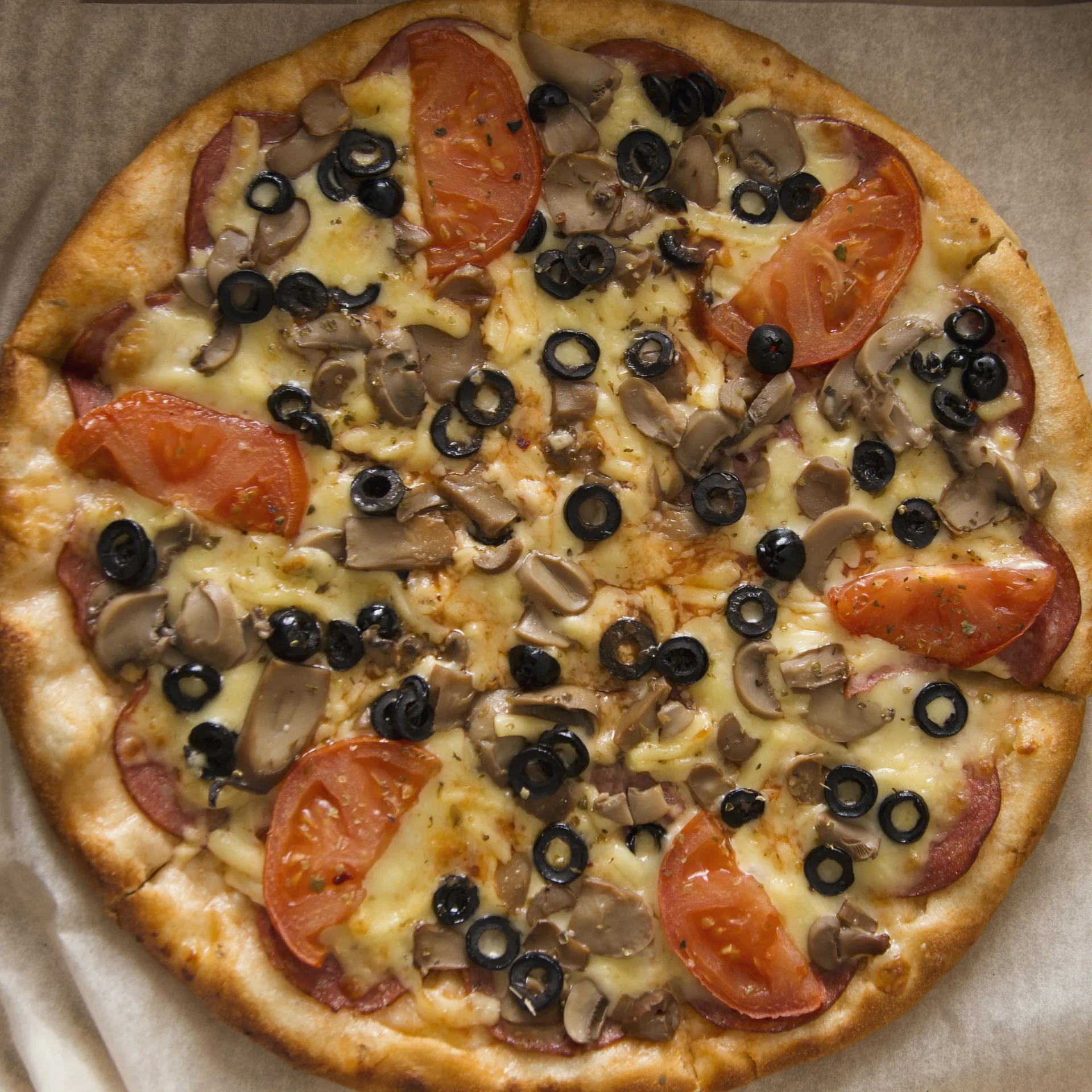 Whole pizza topped with olives, mushrooms and sliced tomato
