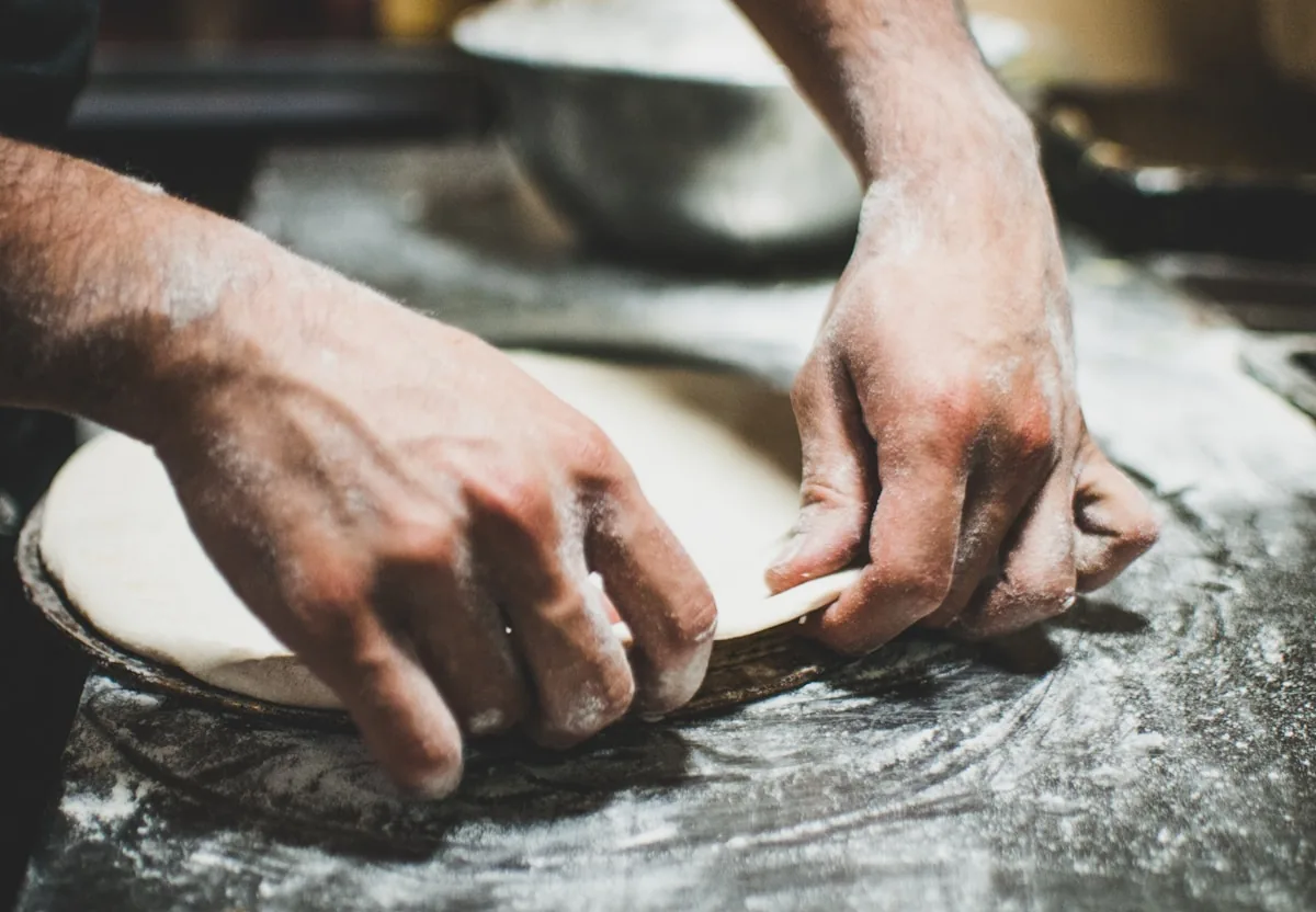 Pizza dough being stretched by hand