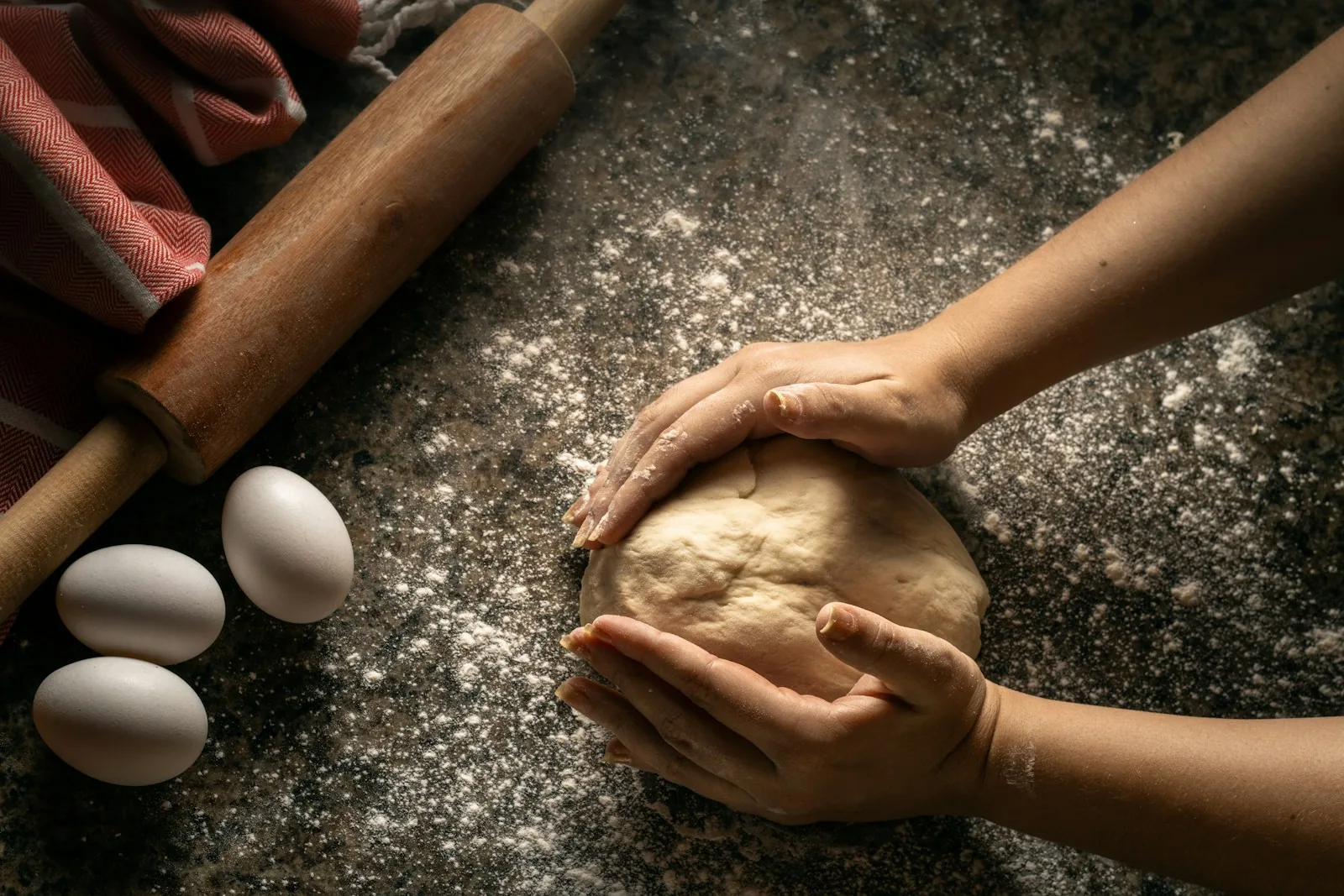 A cook working fresh dough with flour
